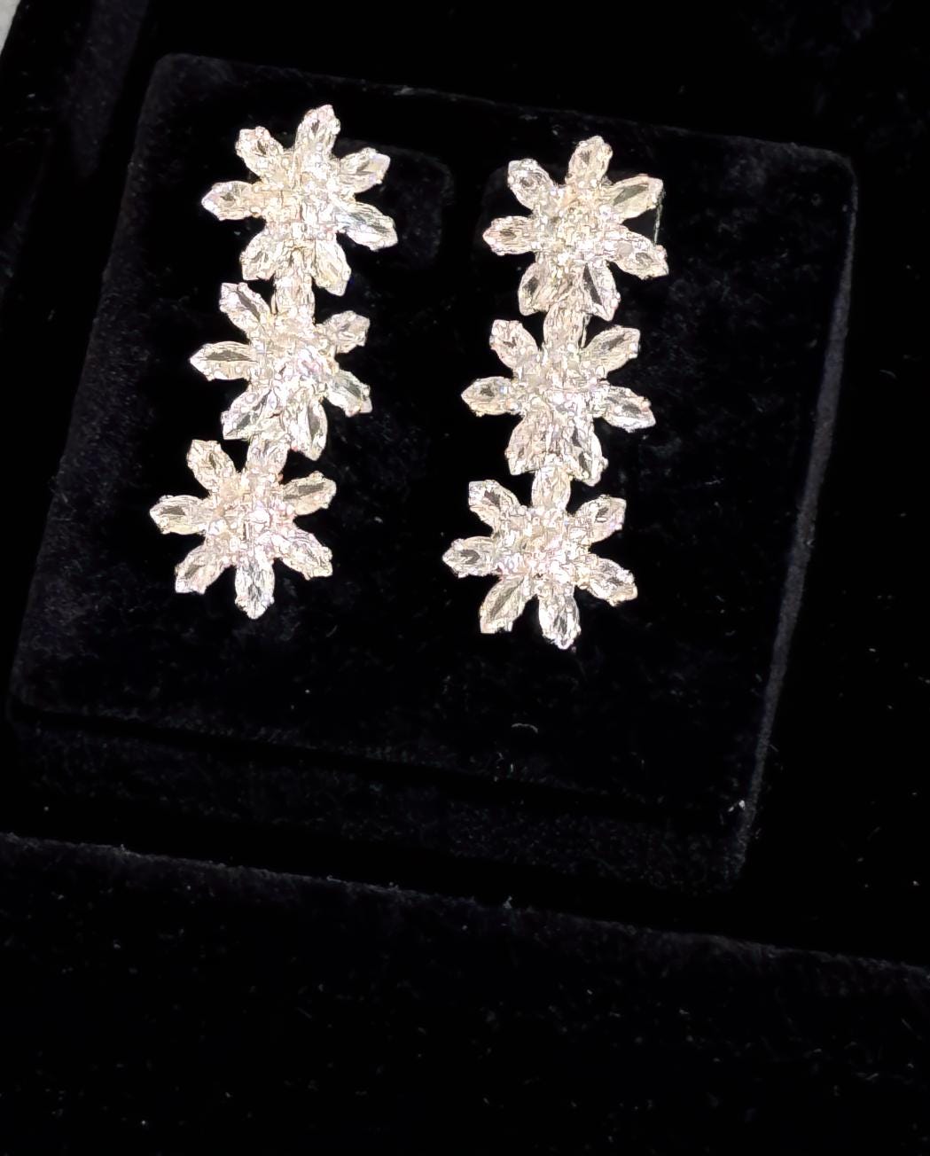 Matching silver floral crystal drop earrings displayed on black velvet