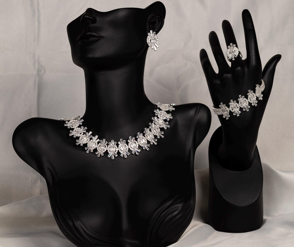 Complete silver crystal jewelry set displayed on black necklace, bracelet and ring stands