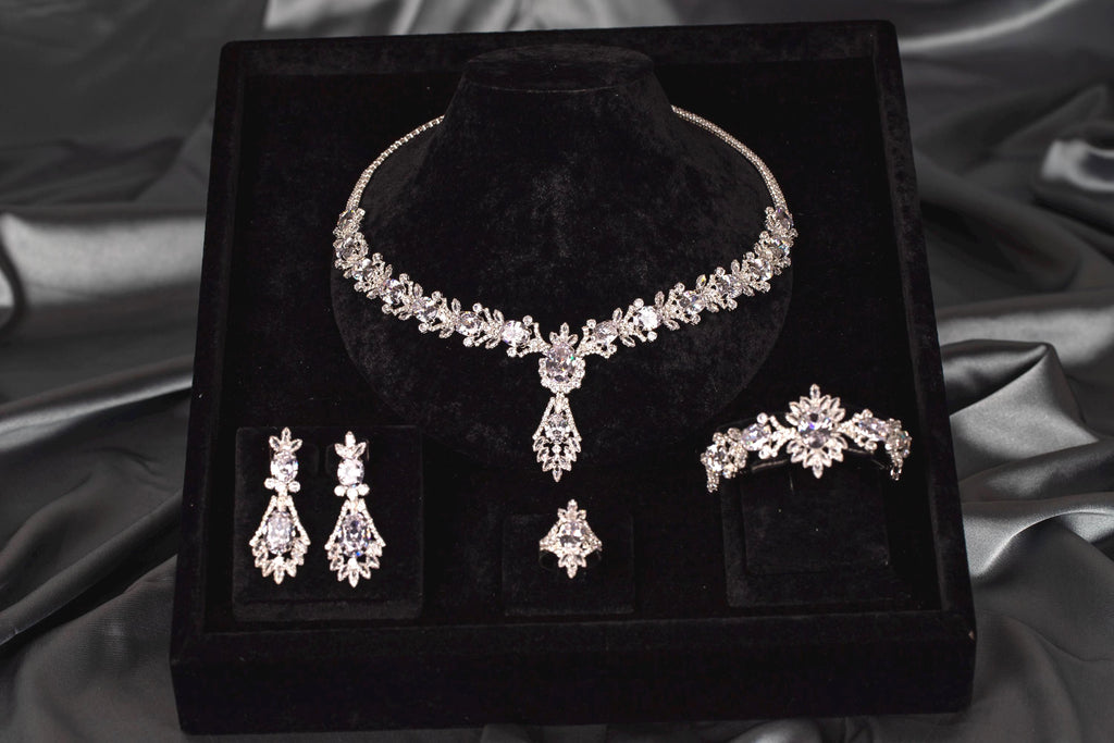 Silver-tone statement necklace with a central teardrop pendant and matching earrings, bracelet and ring on black velvet