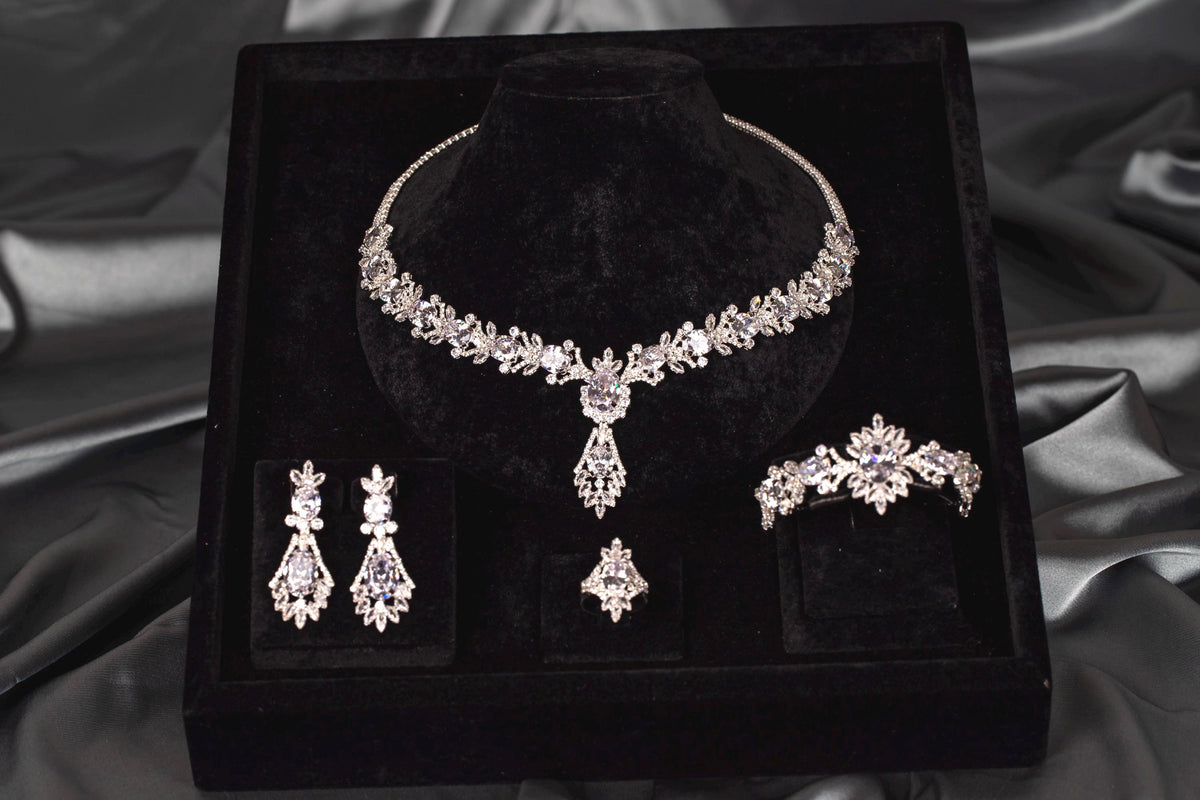 Silver-tone statement necklace with a central teardrop pendant and matching earrings, bracelet and ring on black velvet