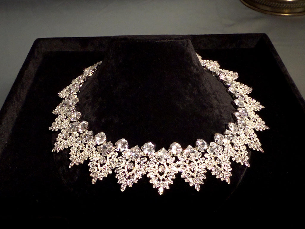 Close-up of a silver-tone bridal necklace showing symmetrical marquise-shaped motifs and intricate crystal detailing
