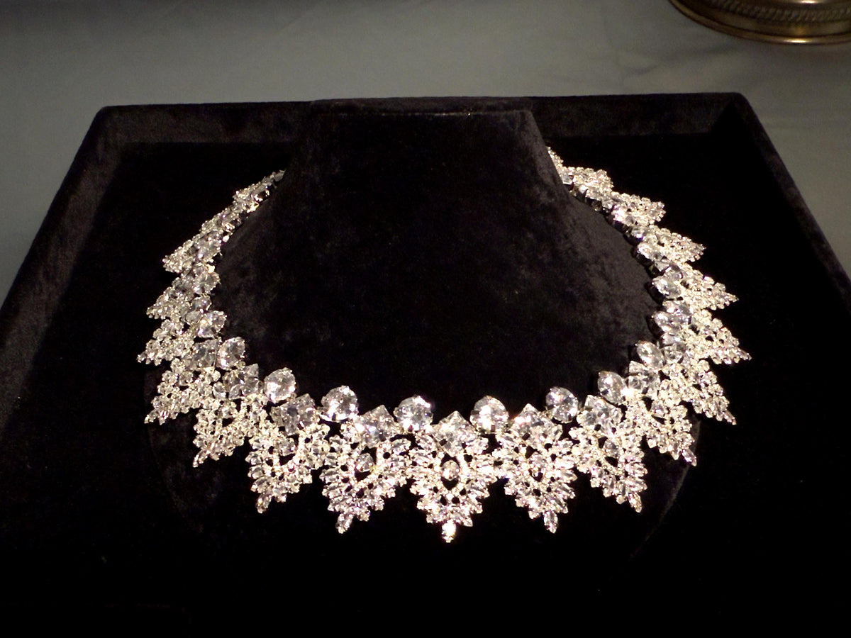 Close-up of a silver-tone bridal necklace showing symmetrical marquise-shaped motifs and intricate crystal detailing

