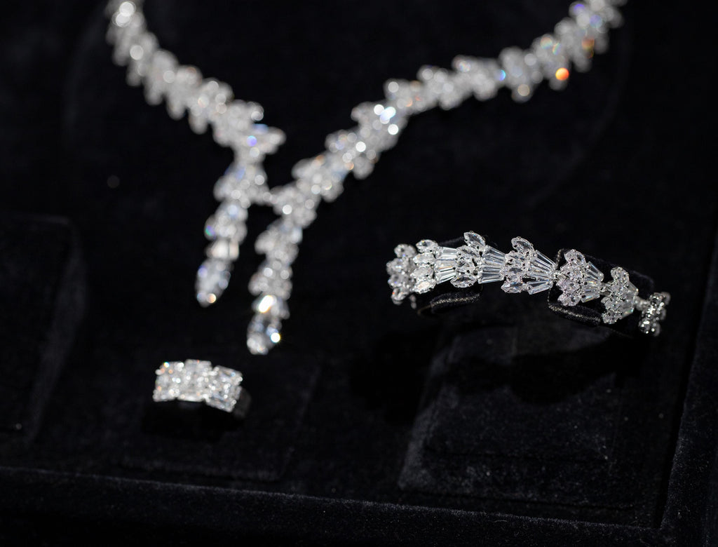 Close-up of a matching baguette zircon bracelet and ring beside the necklace’s two pendant drops in a black velvet box.
