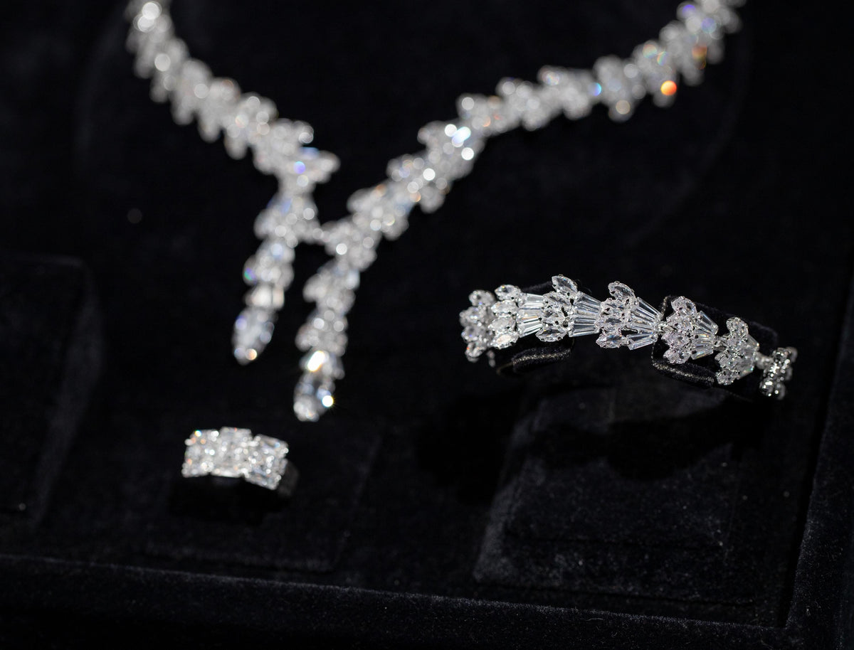 Close-up of a matching baguette zircon bracelet and ring beside the necklace’s two pendant drops in a black velvet box.