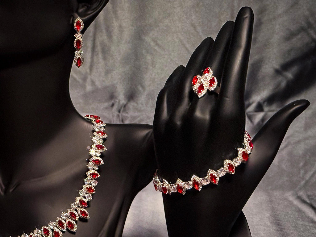 Red zircon halo bracelet and clustered ring on a black hand stand, with the matching necklace and earring alongside.