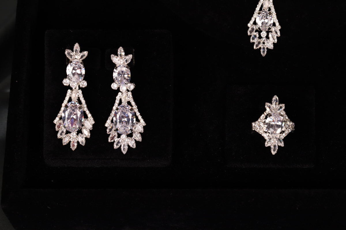 Close-up of silver-tone teardrop earrings and a matching statement ring on black velvet