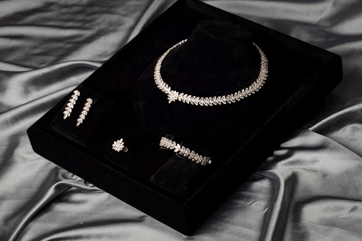 Angled view of a leaf and flower wedding jewelry set in a black presentation box on draped gray satin.