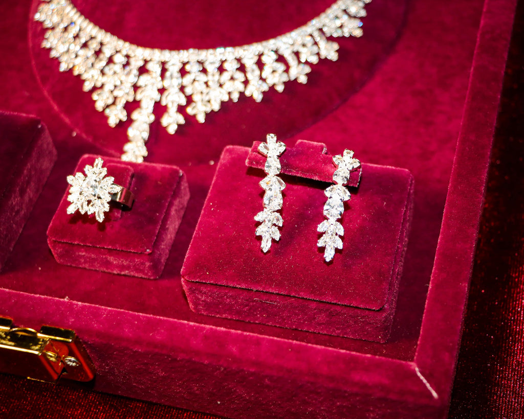 Close-up of floral drop earrings and a matching flower ring beneath the necklace’s cascading zircon details.