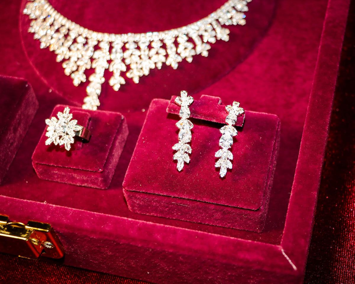 Close-up of floral drop earrings and a matching flower ring beneath the necklace’s cascading zircon details.