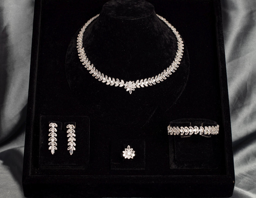 Four-piece leaf and flower bridal jewelry set arranged in a black velvet box, with a necklace, earrings, bracelet and ring.