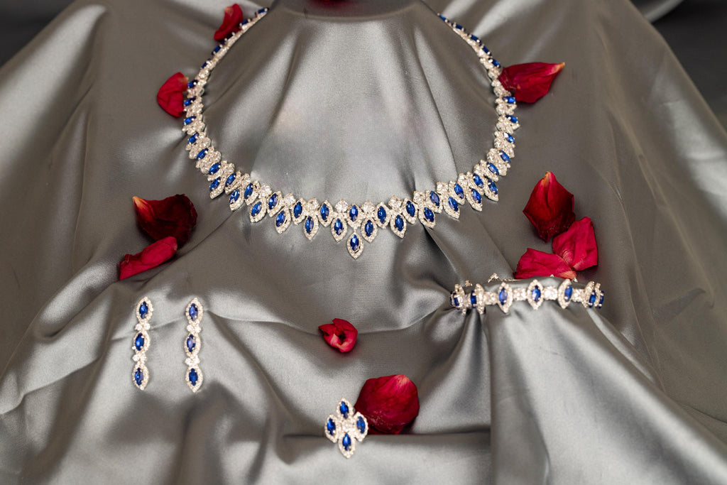 Full view of a blue zircon evening jewelry set on silver-gray satin, with matching accessories below the statement necklace.