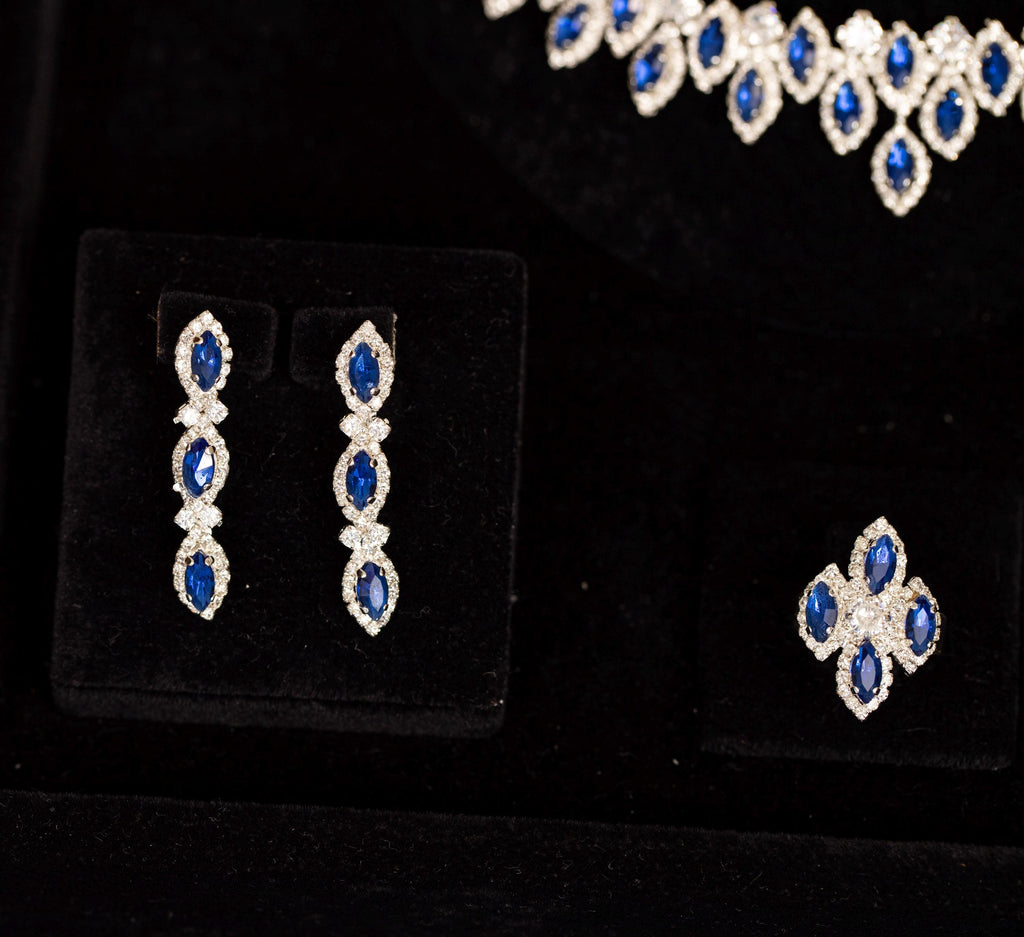Three-stone blue zircon drop earrings and a matching four-stone cluster ring beneath the coordinating halo necklace.