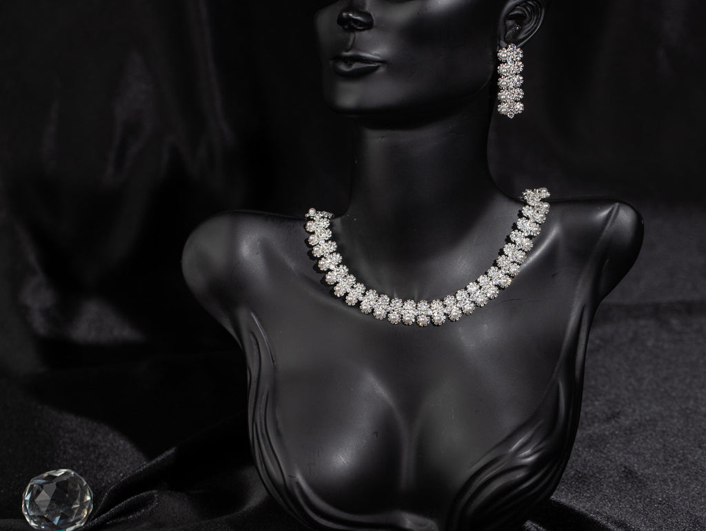 Silver-tone floral faux pearl bridal necklace and matching drop earrings displayed on a black mannequin bust.