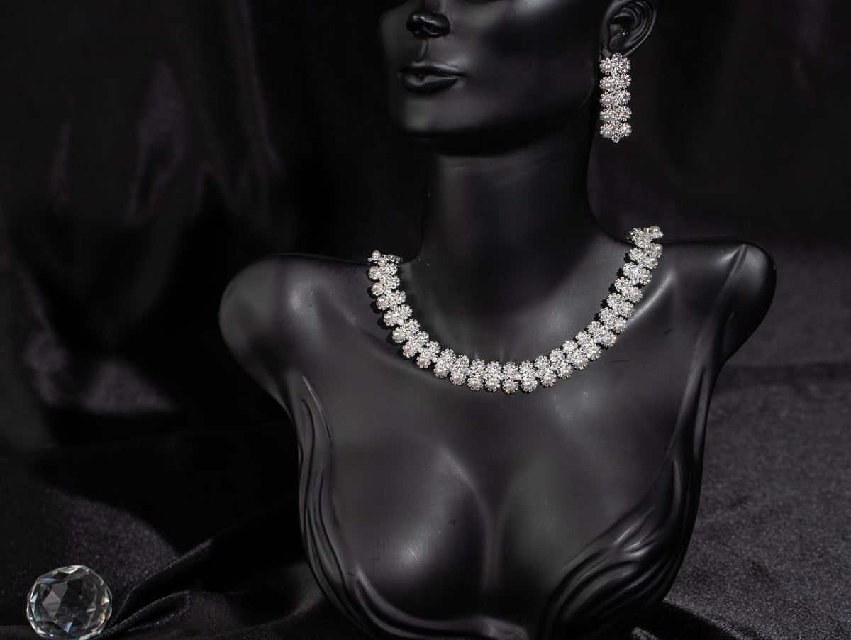Silver-tone floral faux pearl bridal necklace and matching drop earrings displayed on a black mannequin bust.