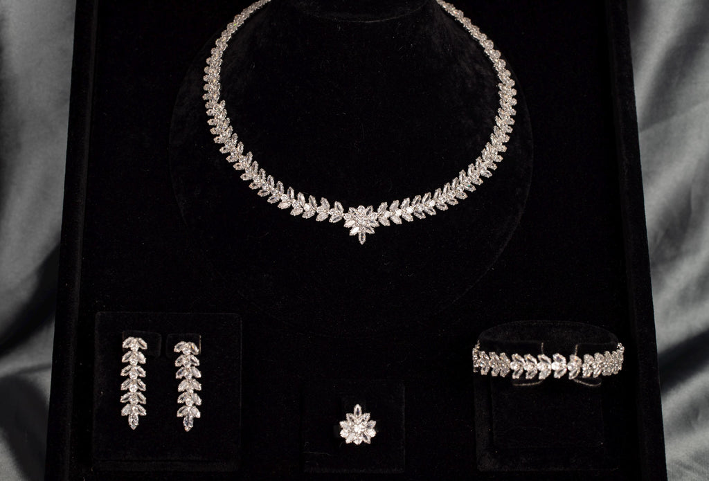 Silver-tone zircon jewelry set on black velvet, showing the floral necklace centerpiece and coordinating leaf details.