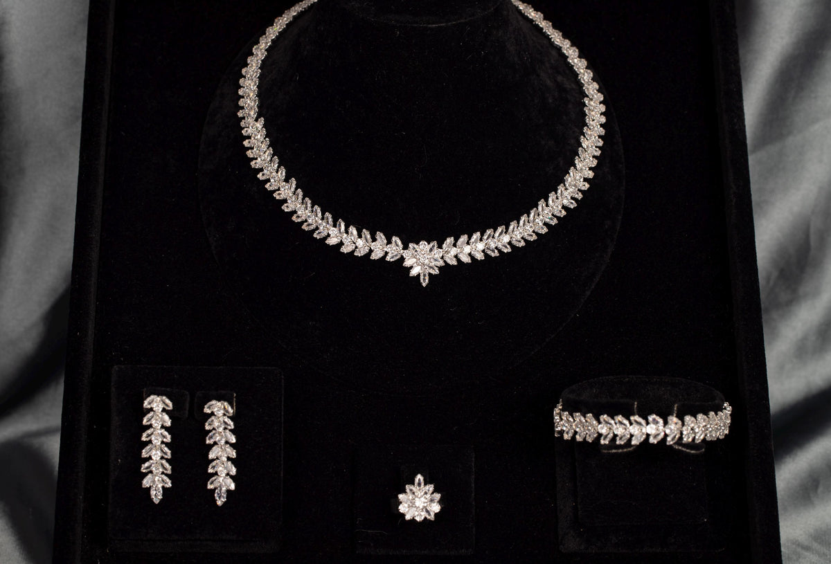 Silver-tone zircon jewelry set on black velvet, showing the floral necklace centerpiece and coordinating leaf details.