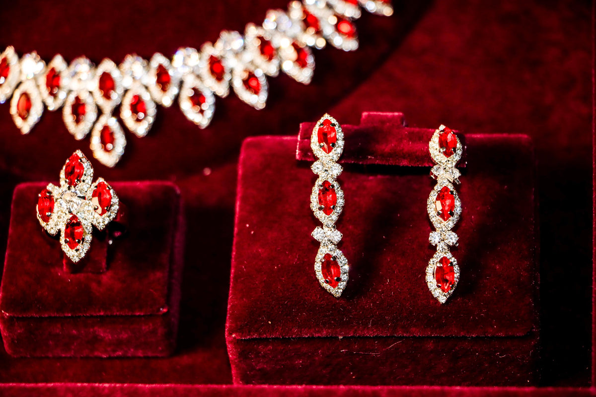 Three-stone red zircon drop earrings and a matching clustered statement ring beneath the coordinating halo necklace.