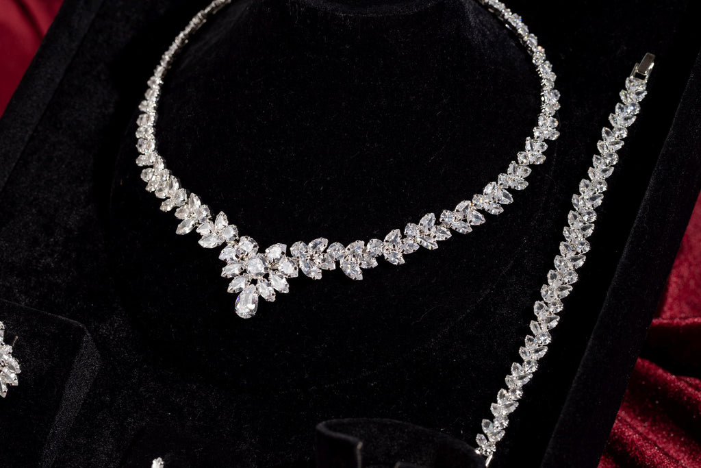 Silver marquise crystal necklace and matching bracelet displayed on black velvet with burgundy satin.