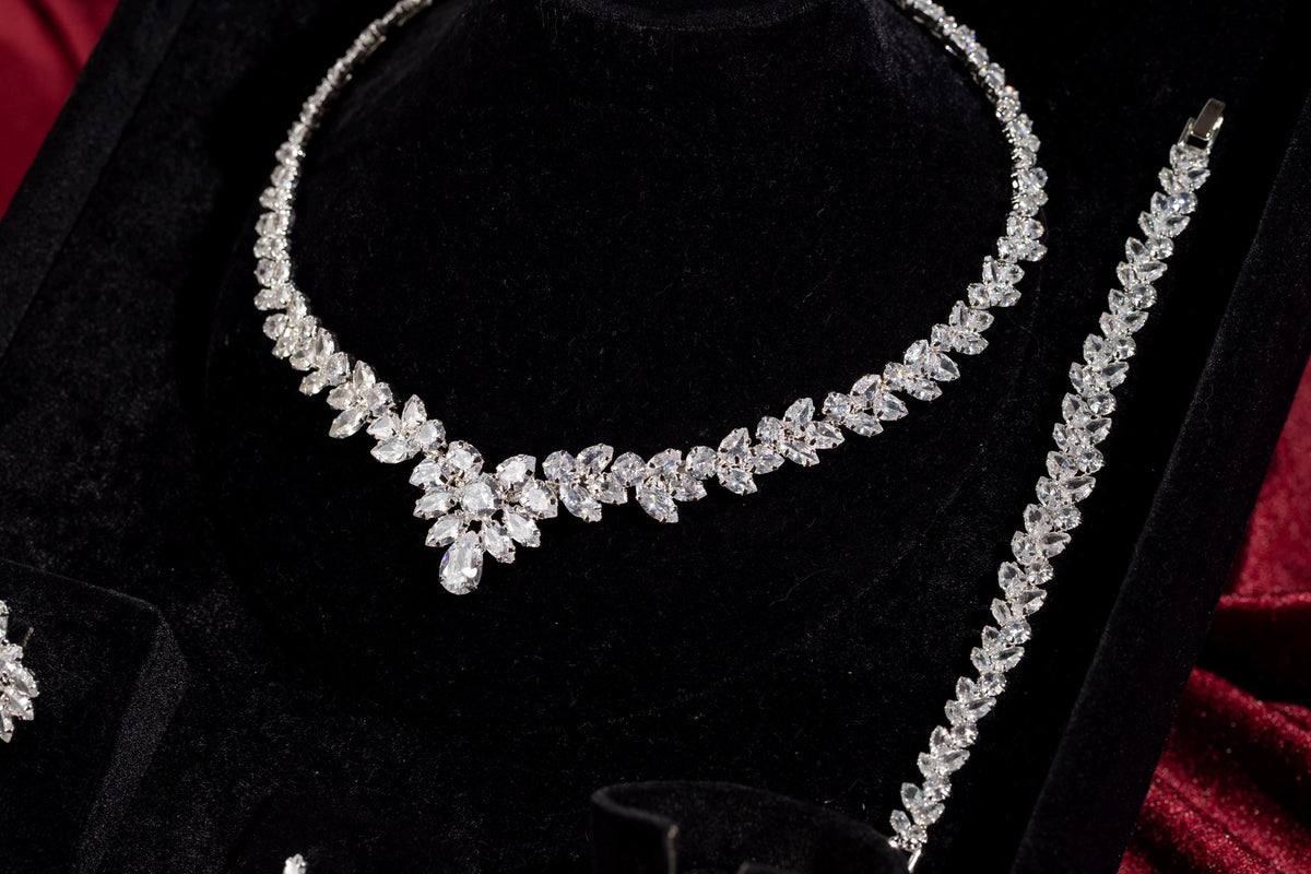 Silver marquise crystal necklace and matching bracelet displayed on black velvet with burgundy satin.