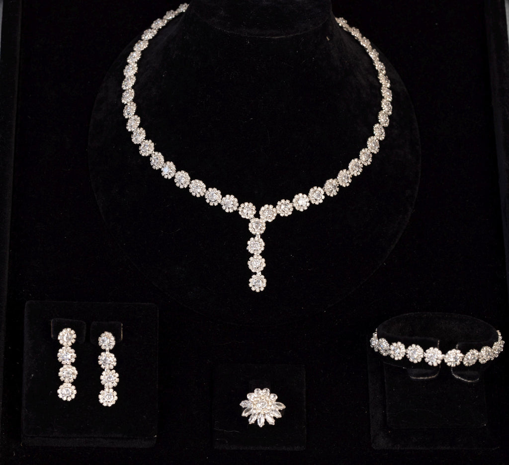 Four-piece silver-tone bridal jewelry set with miniature zircon flowers, displayed together on black velvet.