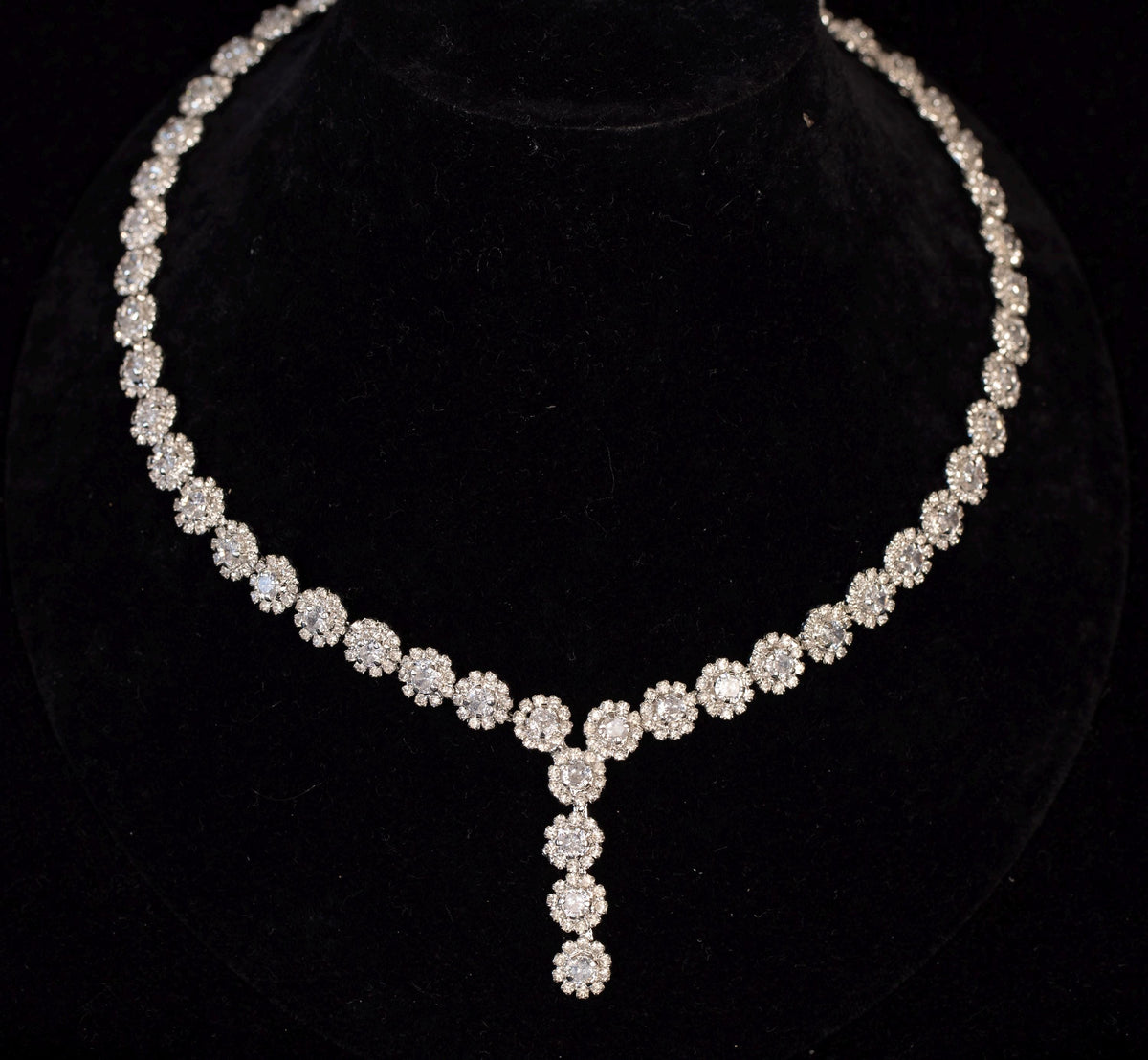 Close-up of a silver-tone necklace formed from miniature zircon flowers with a cascading floral pendant.