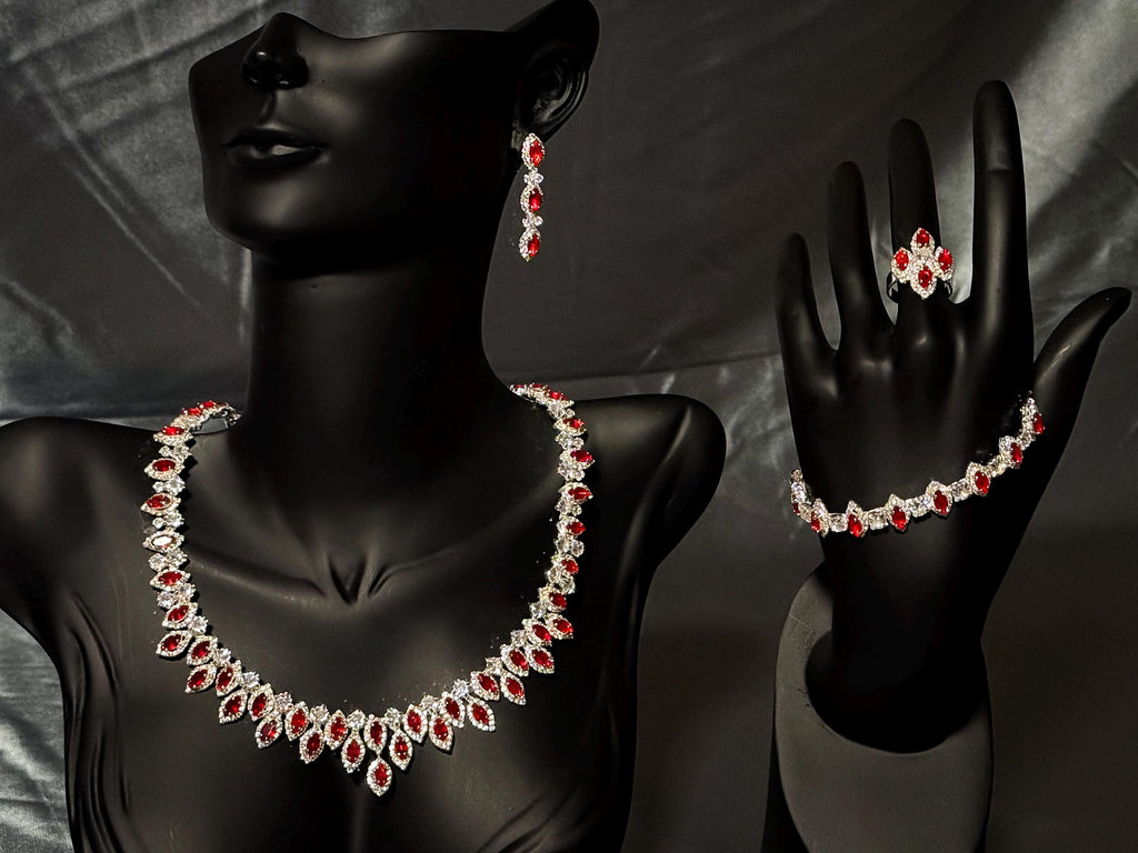 Silver-tone red zircon jewelry set on a black bust and hand stand, showing the necklace, earrings, bracelet and ring.
