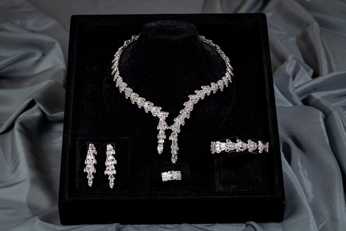 Four-piece baguette zircon bridal jewelry set in a black velvet presentation box surrounded by gray satin.