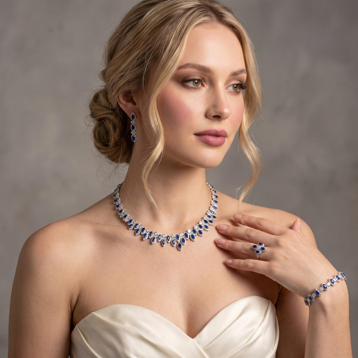 Model in an ivory dress wearing a blue zircon statement necklace with coordinating earrings, bracelet and ring.