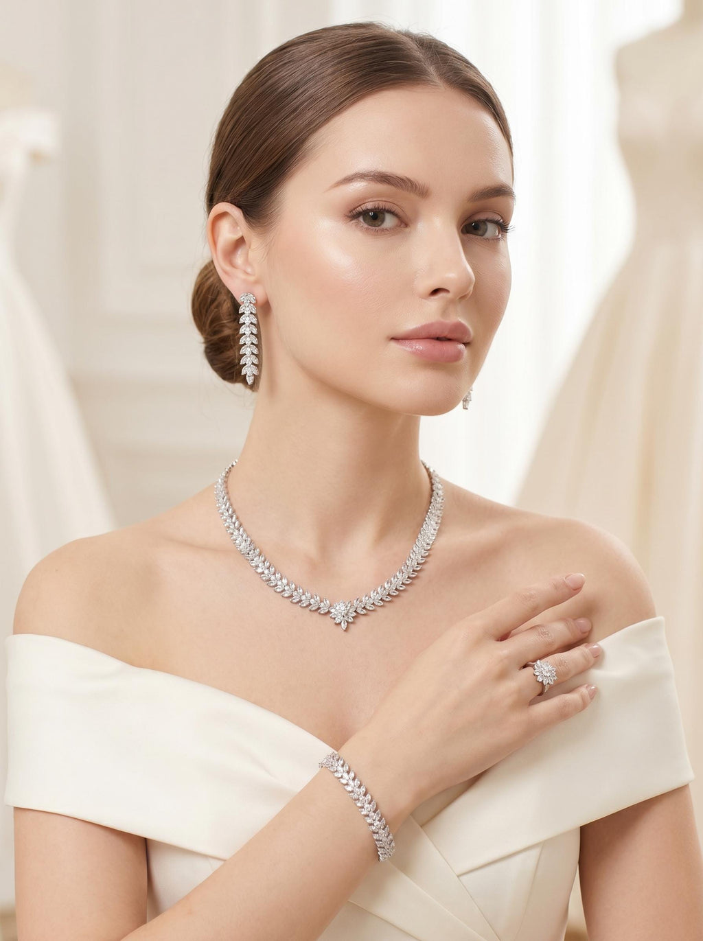 Model in an off-the-shoulder white dress wearing a leaf and flower bridal necklace with matching earrings, bracelet and ring.