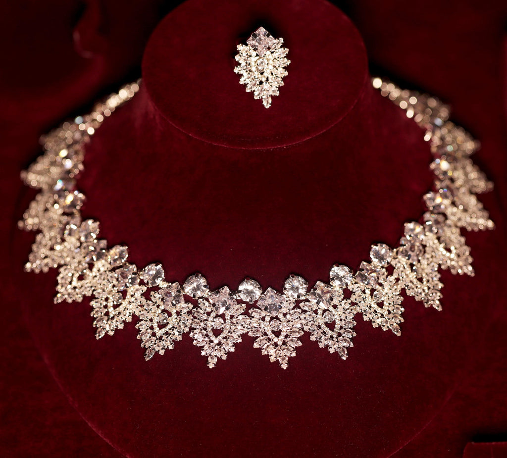 Silver-tone statement bridal necklace and matching ring with intricate marquise-shaped crystal motifs on burgundy velvet
