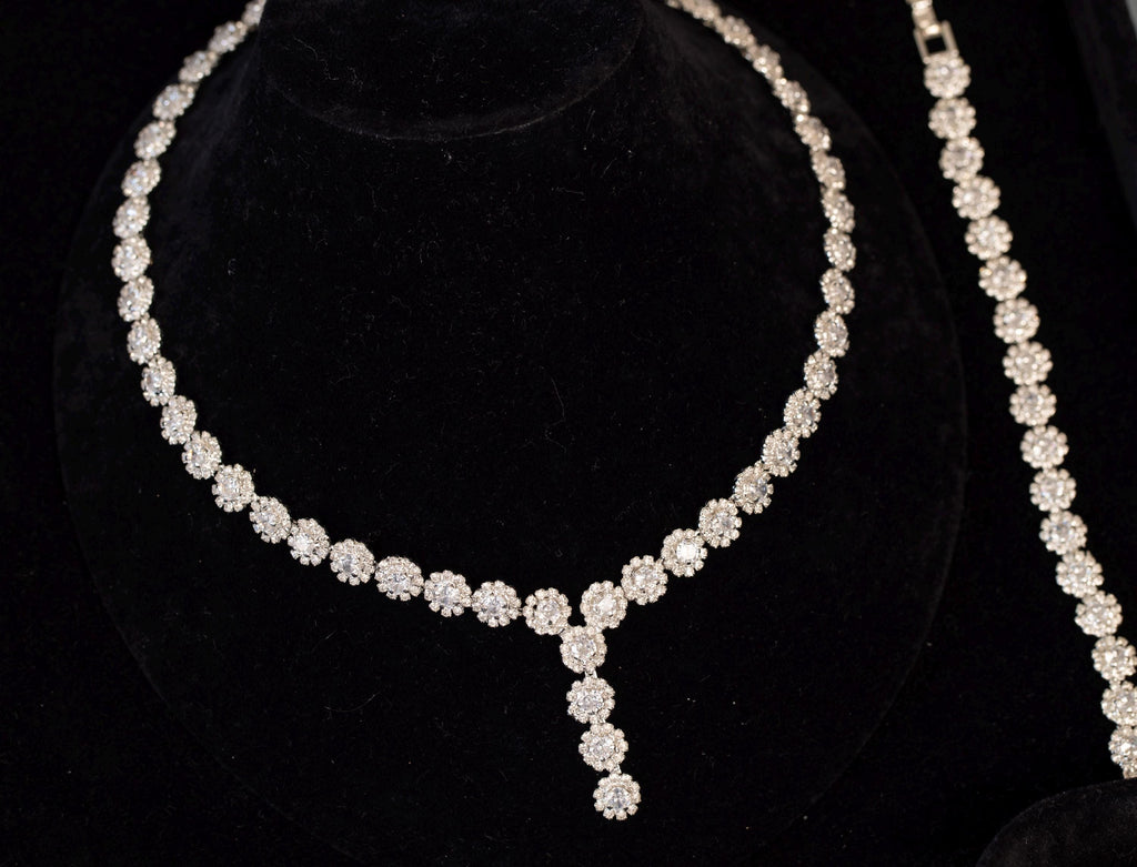 Mini flower Y-shaped bridal necklace on a black velvet bust with a coordinating floral bracelet displayed alongside.