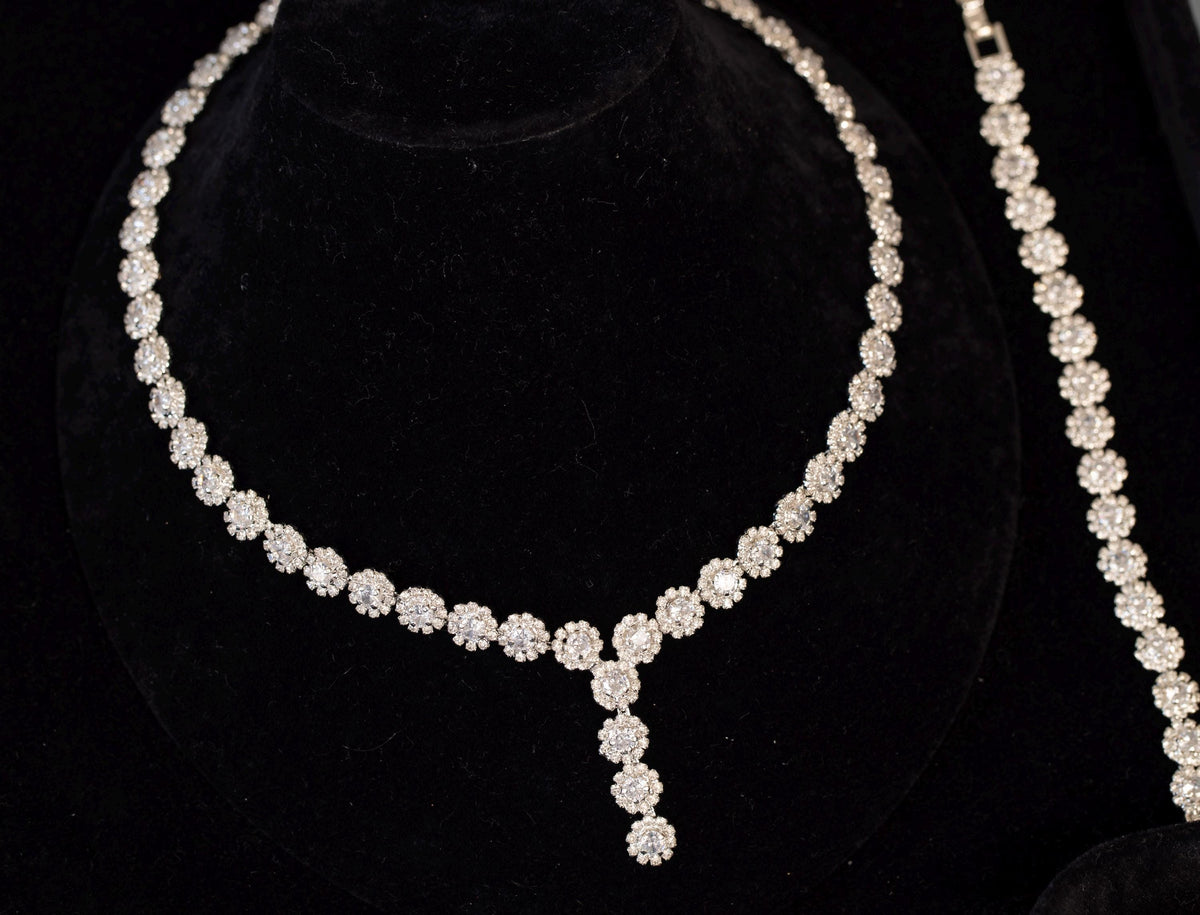 Mini flower Y-shaped bridal necklace on a black velvet bust with a coordinating floral bracelet displayed alongside.