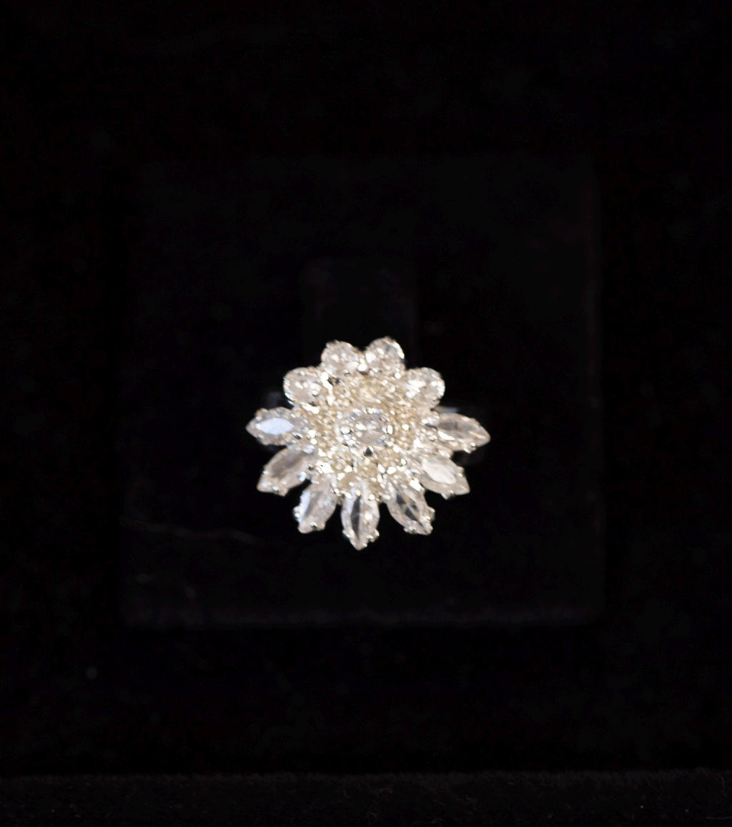 Close-up of a silver-tone floral ring with a sparkling zircon center surrounded by pointed stone petals.