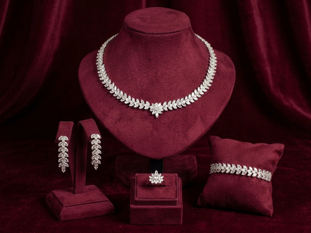 Leaf and flower zircon necklace, drop earrings, bracelet and ring displayed on burgundy velvet jewelry stands.