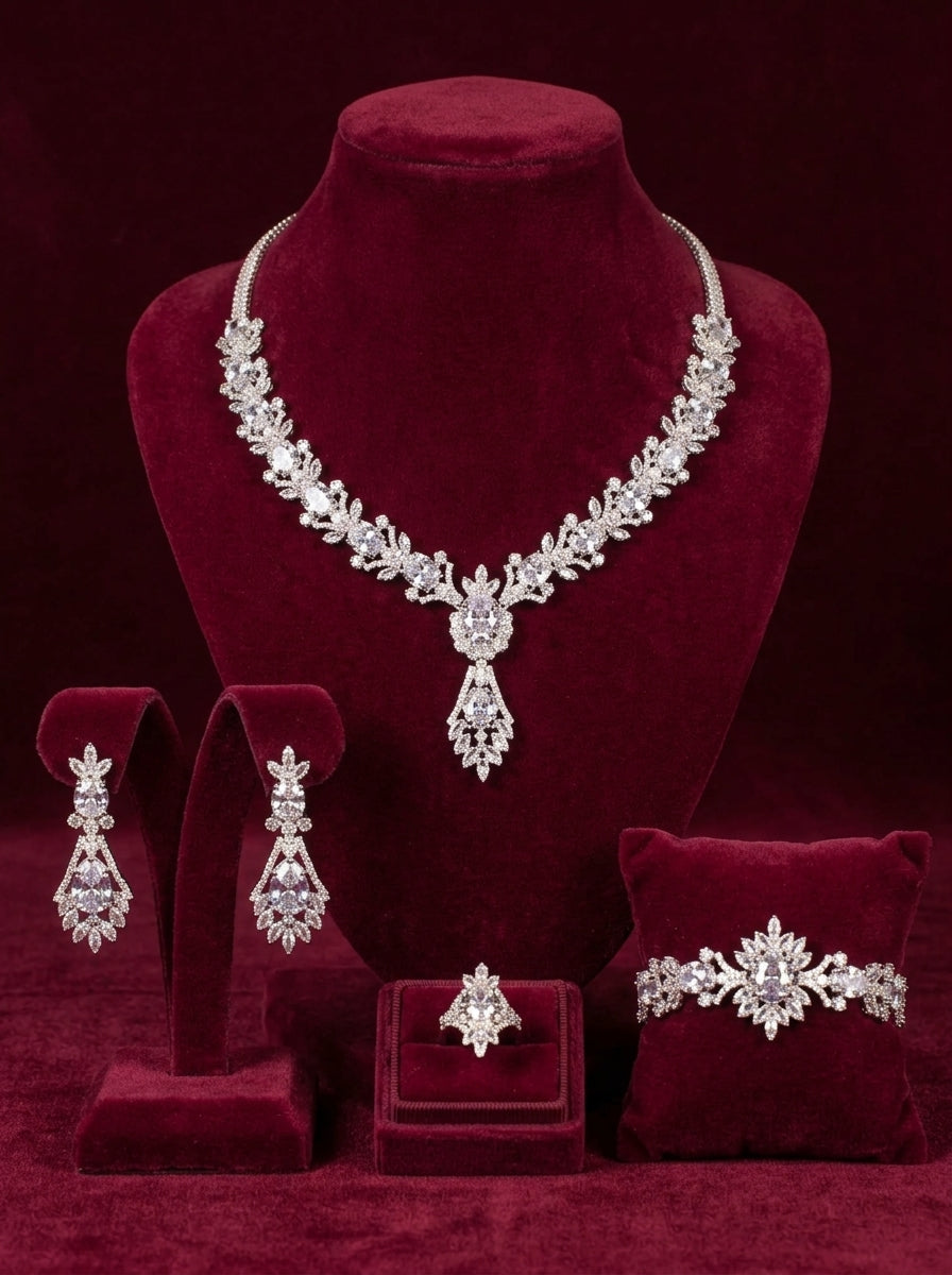 Four-piece silver-tone teardrop jewelry set with necklace, earrings, bracelet and ring on burgundy velvet stands