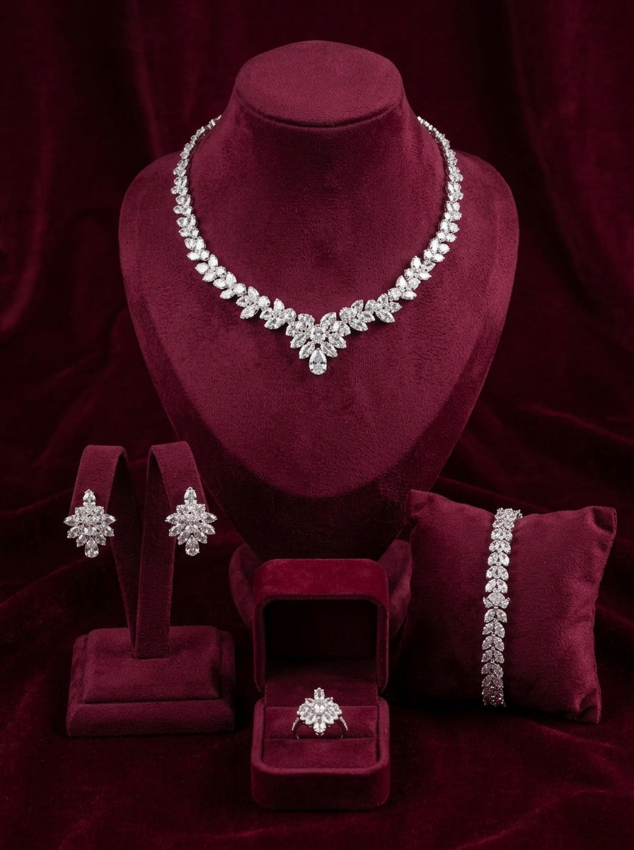 Four-piece silver marquise crystal jewelry set arranged on burgundy velvet display stands.