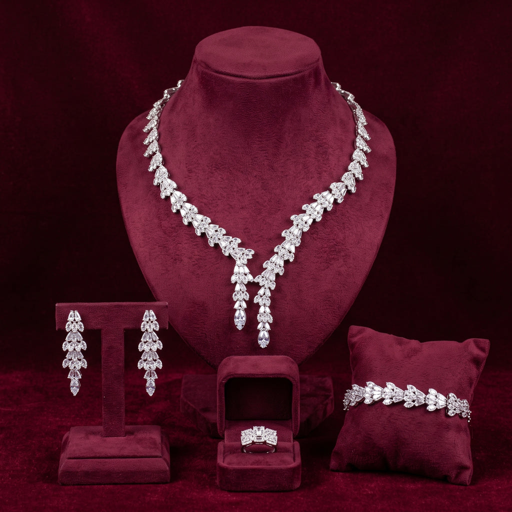Silver-tone baguette zircon necklace with two pendant drops, matching earrings, bracelet and ring on burgundy velvet stands.