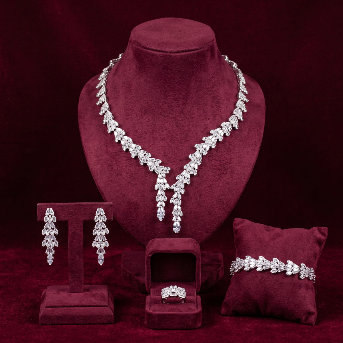 Silver-tone baguette zircon necklace with two pendant drops, matching earrings, bracelet and ring on burgundy velvet stands.