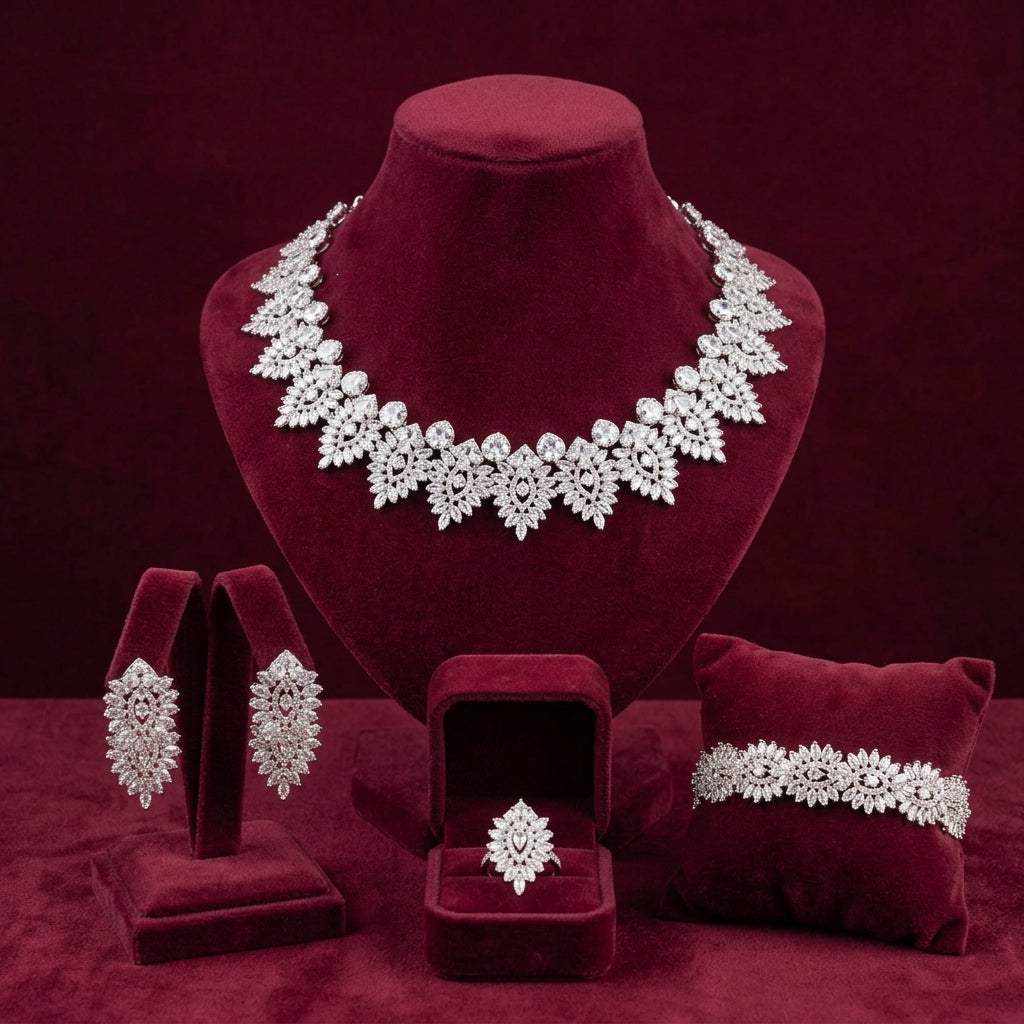 Silver-tone bridal necklace, drop earrings, bracelet and ring with lace-inspired crystal motifs on burgundy velvet
