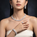 Model wearing a silver-tone floral bridal jewelry set with faux pearls, including necklace, drop earrings, bracelet and ring.