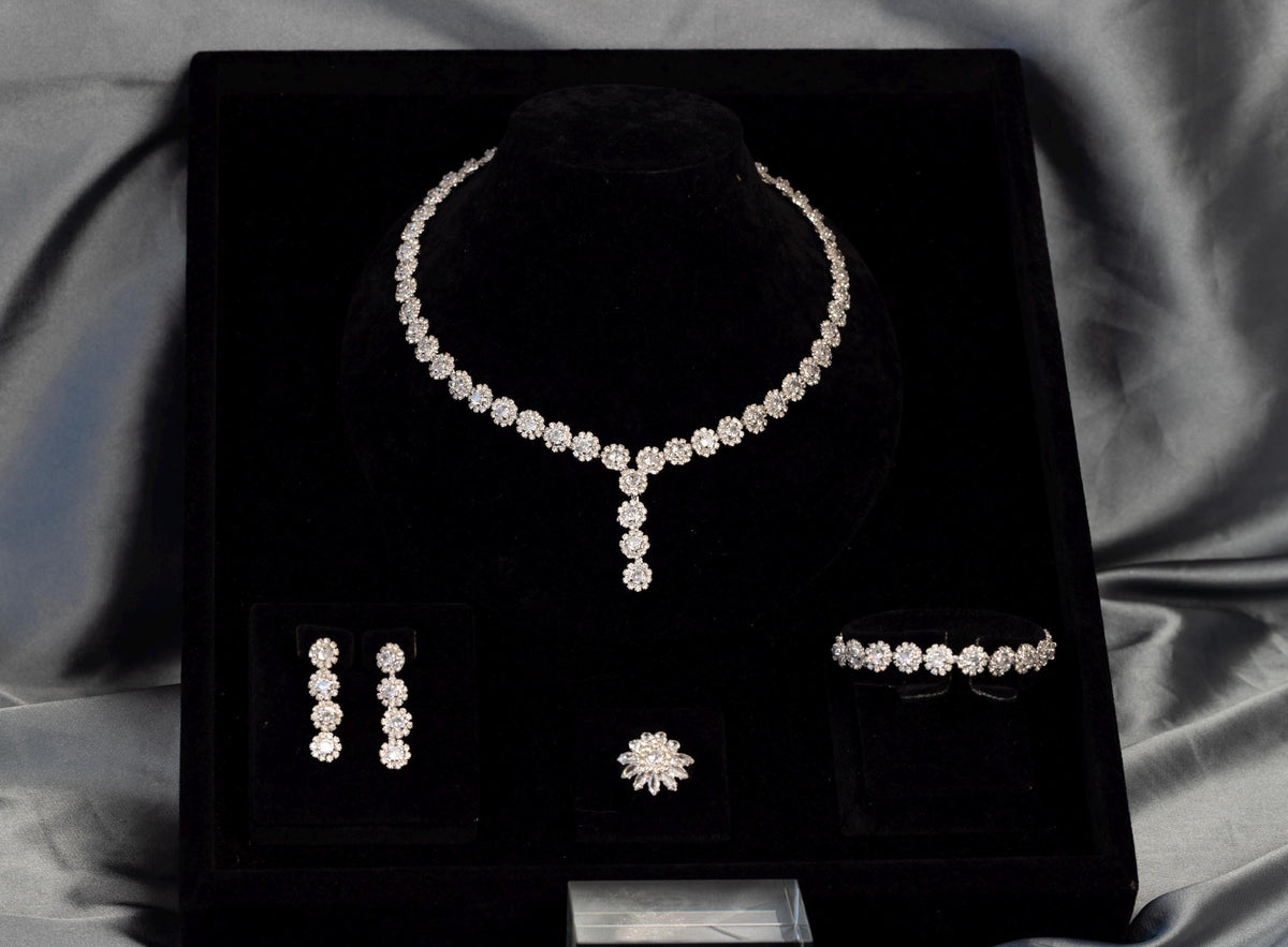 Floral bridal necklace, drop earrings, bracelet and ring in a black presentation box surrounded by gray satin.