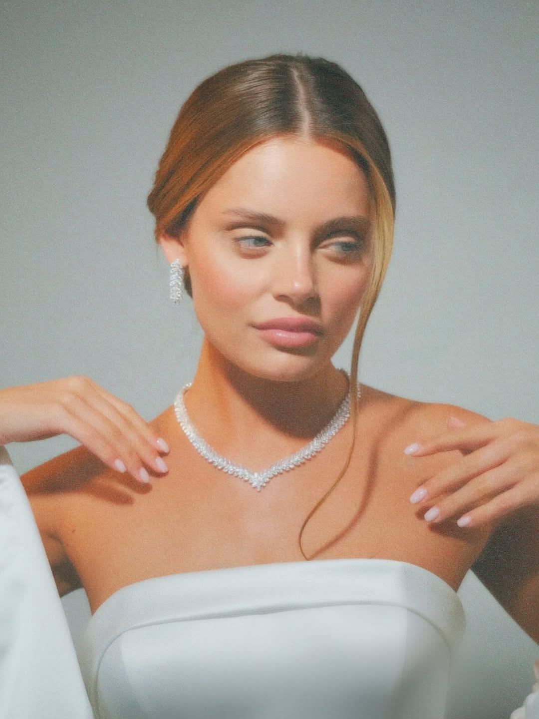 Model in a wedding dress wearing a delicate leaf and flower necklace with matching zircon drop earrings.