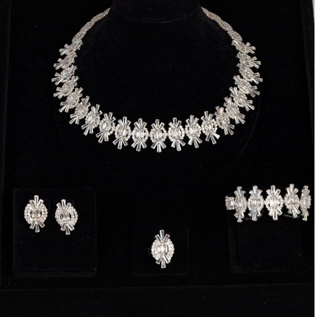 Silver bridal jewelry set with necklace, earrings, bracelet and ring arranged on black velvet