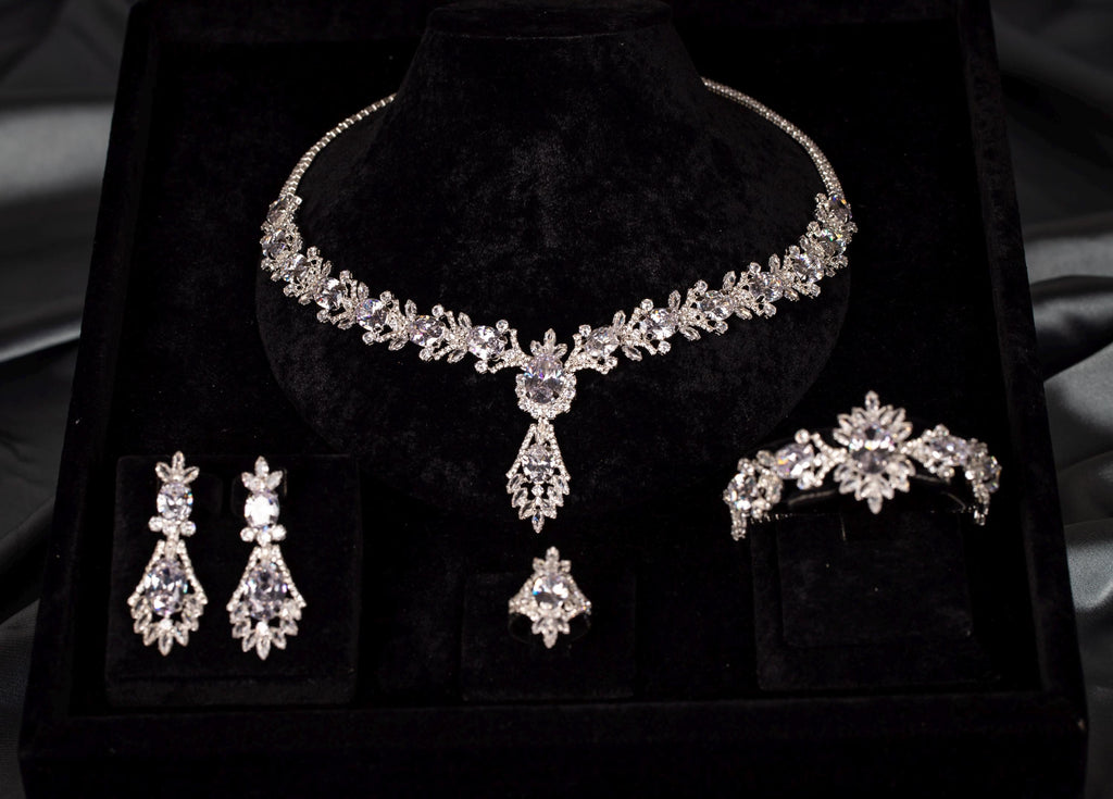 Front view of a silver-tone teardrop necklace, matching drop earrings, bracelet and ring with clear sparkling stones