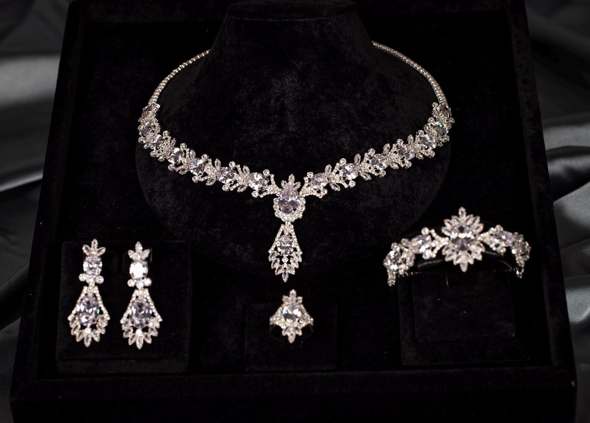Front view of a silver-tone teardrop necklace, matching drop earrings, bracelet and ring with clear sparkling stones