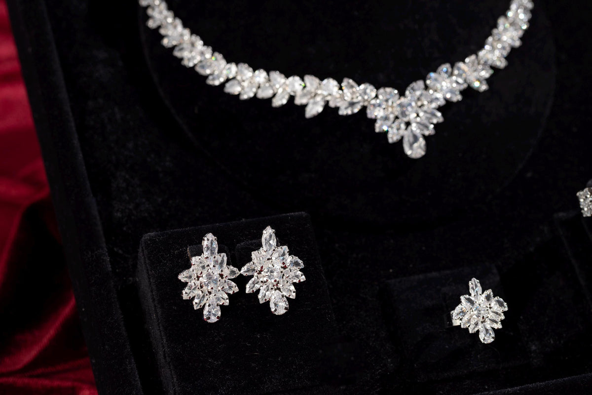 Silver marquise crystal necklace, earrings and ring displayed on black velvet with burgundy satin.