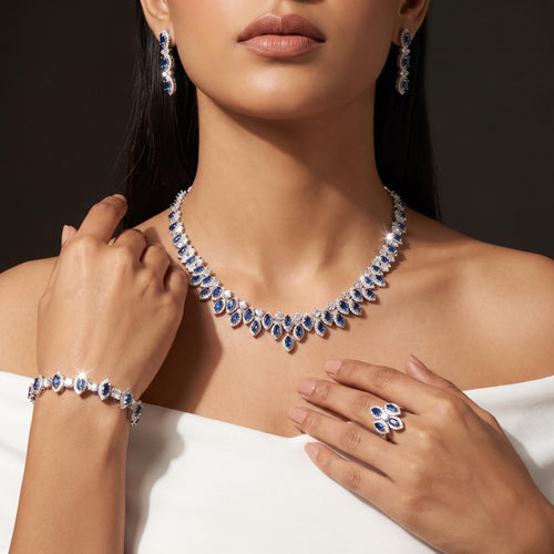 Model wearing a blue zircon halo necklace with matching drop earrings, bracelet and cluster ring in a silver-tone finish.