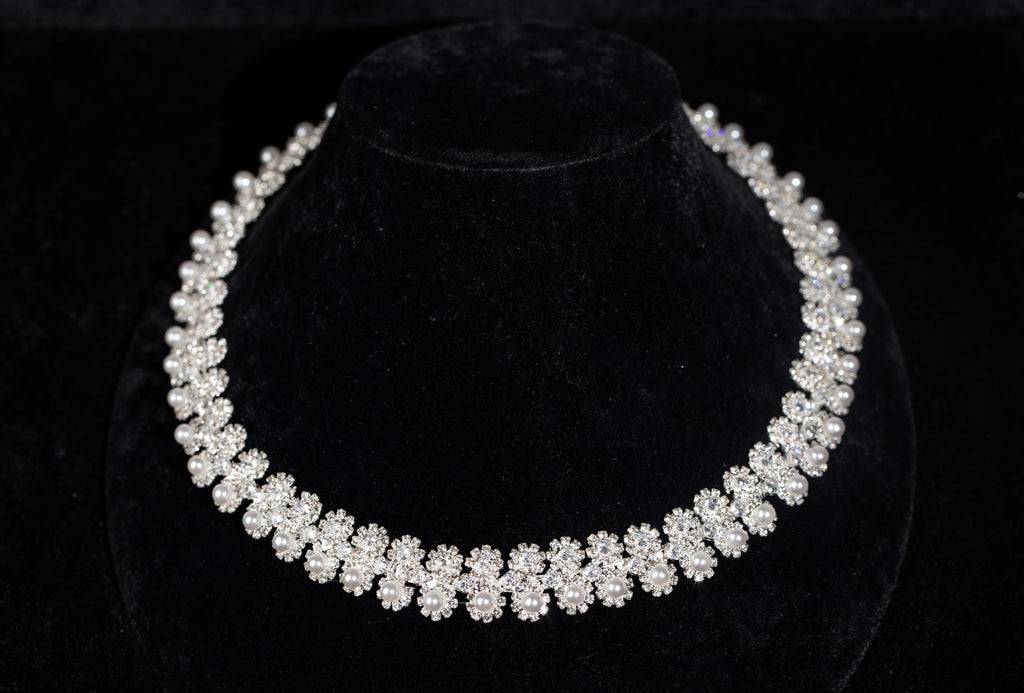 Silver-tone bridal necklace with miniature zircon flowers and white faux pearl accents on a black display bust.