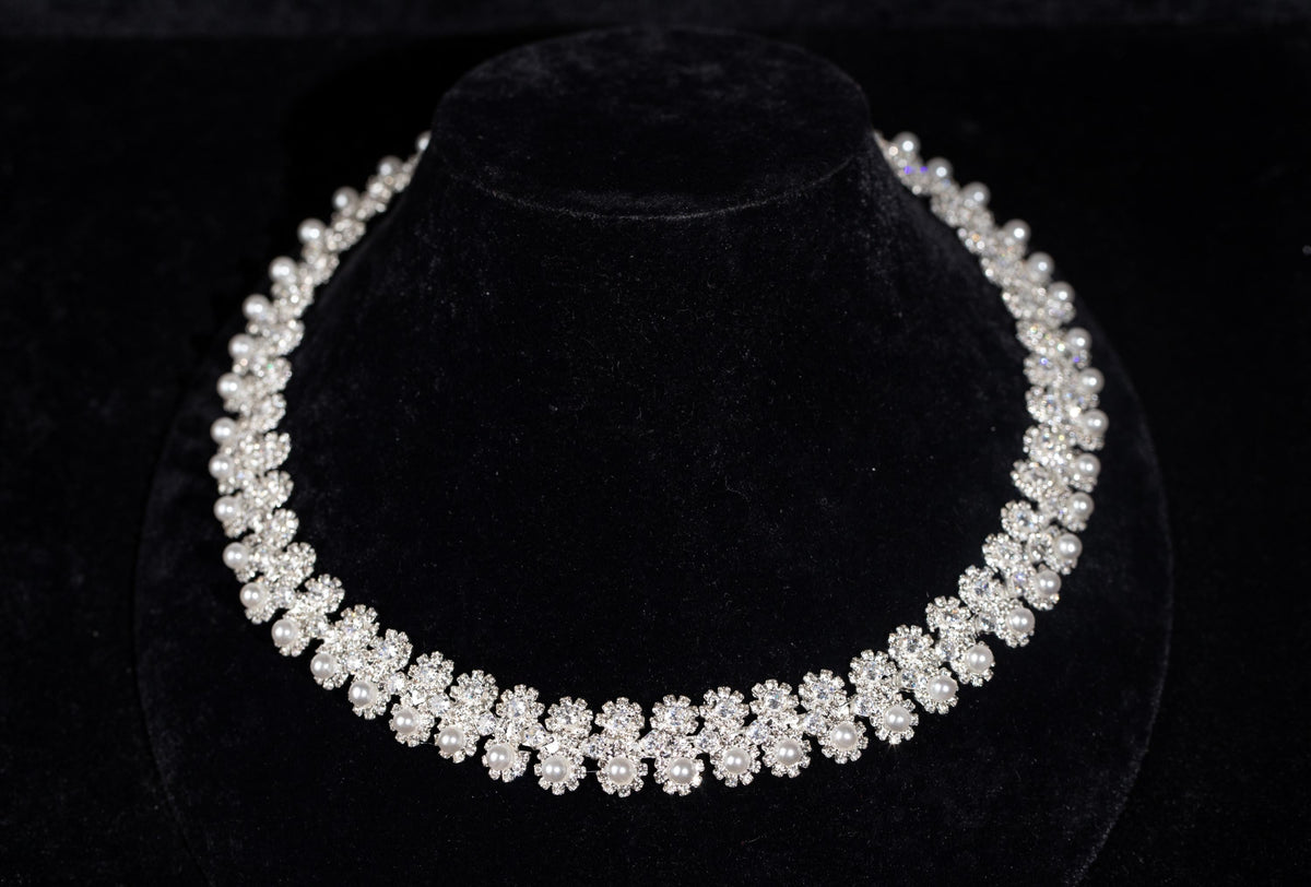 Silver-tone bridal necklace with miniature zircon flowers and white faux pearl accents on a black display bust.