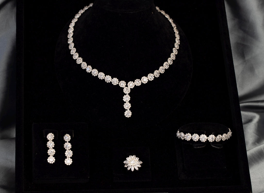 Angled view of a floral Y necklace with matching drop earrings, bracelet and flower ring in a black velvet display.